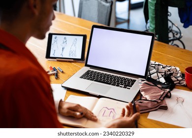 Close up of biracial transgender fashion designer using tablet and laptop with copy space on screen. Gender, fashion, design, communication and lifestyle. - Powered by Shutterstock