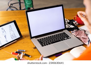 Close up of biracial transgender fashion designer using tablet and laptop with copy space on screen. Gender, fashion, design, communication and lifestyle. - Powered by Shutterstock