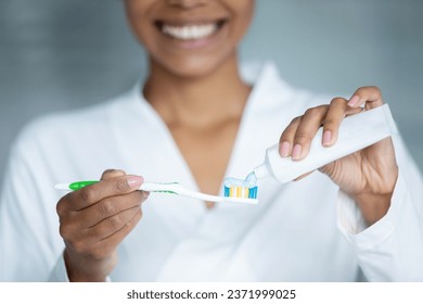 Close up of biracial woman squeeze put toothpaste on toothbrush recommend brush teeth for healthy white smile, happy african American female take care of oral hygiene, do daily morning routine in bath - Powered by Shutterstock