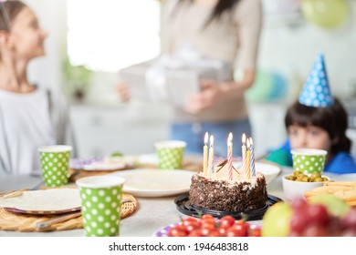 Close Up Of A Birtday Cake With Candles On The Table. Happy Latin American Family With Children Celebrating Birthday At Home