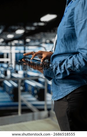 Close up of black admin using tablet to do infrastructure AI machine learning automatization in server farm, doing maintenance using neural network systems. Data center software developer.