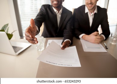 Close up of black businessman offering job, reaching out employment agreement to successful applicant, labor contract of work, extending hand for handshake, hiring new employee, getting job