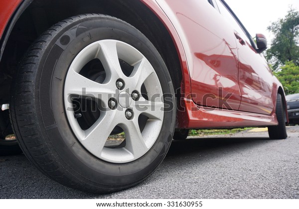 Close up of a black car tyre park on the road.Red\
car tyre in black.