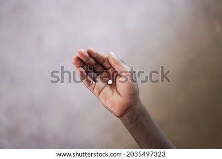 Close up of a black child's hand holding a single pill; African healthcare concept