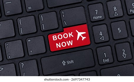 Close up of black computer keyboard featuring red book now button with airplane icon for online flight reservation travel concept