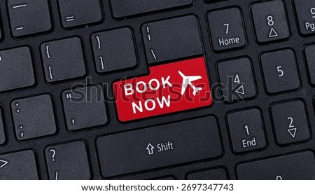 Close up of black computer keyboard featuring red book now button with airplane icon for online flight reservation travel concept