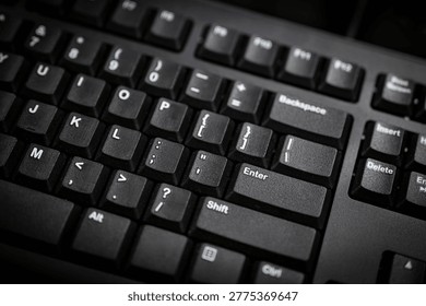 Close up of black computer keyboard with focus on enter and function keys, representing typing, technology, data input, and modern digital workspace in low light environment.
