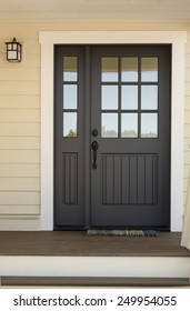 Close Up Of Black Front Door On House With Yellow Exterior Siding