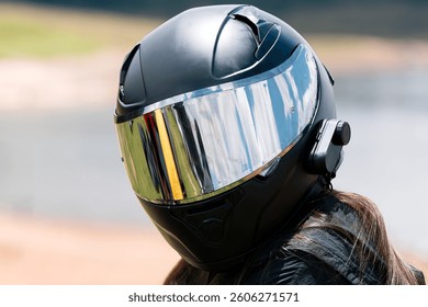 Primer plano de un casco de motocicleta de cara completa negro con una visera reflectante y un sistema de intercomunicación, que garantiza la seguridad y la comunicación en la carretera