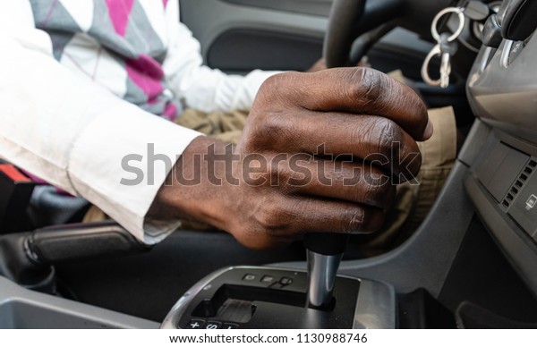 Close up of Black male driver hand on\
manual gear shift knob or Business man driver hand shifting the\
gear stick. African American Driver\'s hand changing\
speed