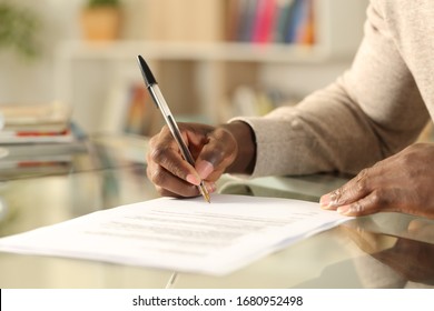 Close up of black man hands signing document on a desk at home - Shutterstock ID 1680952498