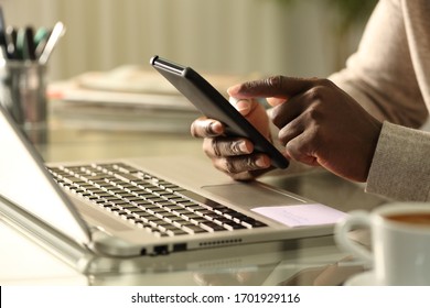 Close Up Of Black Man Hands Using Smart Phone With Laptop At Home