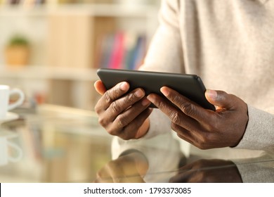 Close Up Of A Black Man Hands Watching Video On A Smart Phone Sitting On A Desk At Home