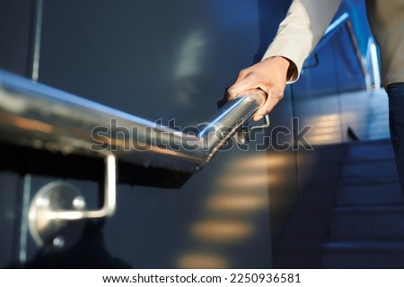 Close up of a black man's hand gripping the railing of some stairs. Handle concept.