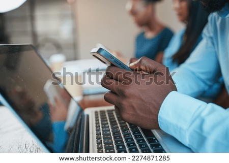Close up of Black man's hands using phone during meeting, with laptop