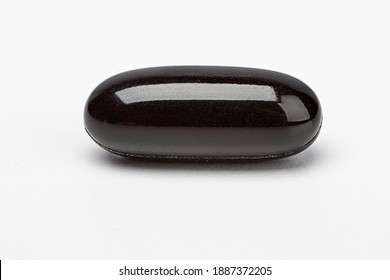 close up of a black omega pill supplement against a white background