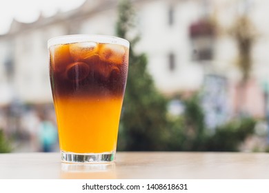 Close up black orange coffee, cold coffee cocktail on blurred city street background. Selective focus - Shutterstock ID 1408618631