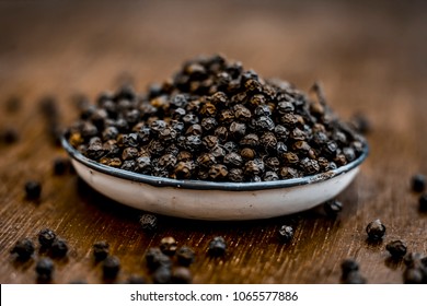 Close up of black peppercorns or kali mari on wooden surface with its extracted herbal beneficial oil.