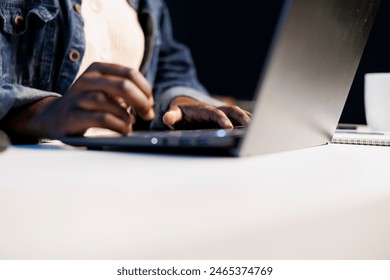 Close up of black person utilizing modern technology by typing on portable computer. Selective focus on hands of african american individual taking notes on laptop and surfing the net. - Powered by Shutterstock