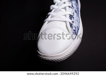 Close up of black and white shoe sneakers on black background.