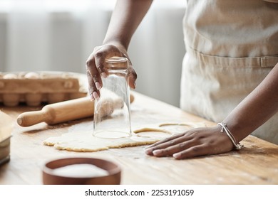 Close up of black woman baking homemade pastry and cutting cookie shapes on wooden kitchen counter, copy space - Powered by Shutterstock