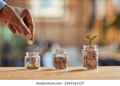 Close up of black woman hand adding money in coin in a jar. Girl hand holding coin adding money in glass jar of different sizes. Investment, savings and interest concept.