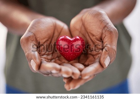 Close up of black woman hands holding a small red heart. Small heart in the hands of a african woman. Solidarity, charity and responsibility concept.