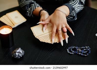 Close Up Of Black Woman Holding Tarot Cards Over Table In Fortune Tellers Shop Lit By Candles, Copy Space