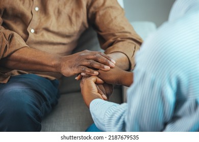 Close up black woman and man sitting on couch two people holding hands. Symbol sign sincere feelings, compassion, loved one, say sorry. Reliable person, trusted friend, true friendship concept - Shutterstock ID 2187679535