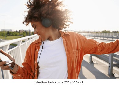 Close up of black woman wearing headphones and dancing on the bridge - Powered by Shutterstock