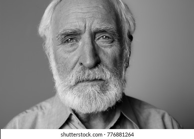 Close up black-and-white portrait of sorrowful man looking at camera while standing. Isolated on grey background