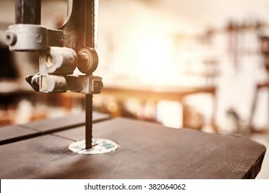 Close Up Of The Blade Of A Jig Saw In A Woodwork Workshop, With Sunflare In The Background