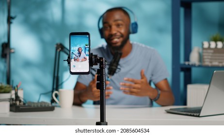 Close up of blogger filming video with smartphone on tripod for online vlog. Content creator using mobile phone and videography equipment to record for podcast channel on social media. - Shutterstock ID 2085604534