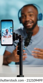 Close up of blogger filming video with smartphone on tripod for online vlog. Content creator using mobile phone and videography equipment to record for podcast channel on social media. - Shutterstock ID 2121094991