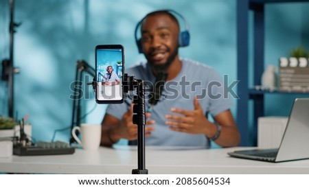 Close up of blogger filming video with smartphone on tripod for online vlog. Content creator using mobile phone and videography equipment to record for podcast channel on social media. [[stock_photo]] © 
