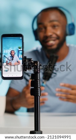 Close up of blogger filming video with smartphone on tripod for online vlog. Content creator using mobile phone and videography equipment to record for podcast channel on social media.