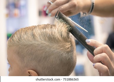 Close up of blond kid getting haircut at hairdresser's. 