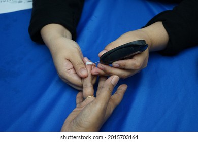 Close Up Blood Withdraw From Patient's Finger Onto Glucometer Blood Strip.                      