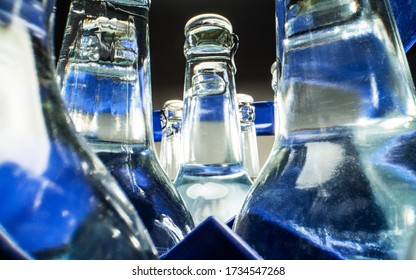 Close Up Of Blue Case Of Transparent Glass Bottles Filled With Mineral Water. 