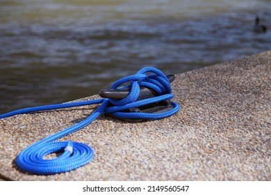 Close up of a blue electric sailor's knot with the rest of the rope rolled up on the water