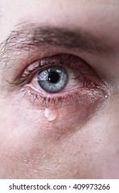 close up of blue eye of man crying in tears sad and full of pain in depression tragedy and tragic problem concept