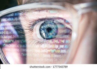 Close Up Of Blue Hacker Eye With Glasses. Reflection Of Computer Code In Glasses. Focused On Work Software Developer Looking At The Computer. Hacking, Vision And Technology Concept 