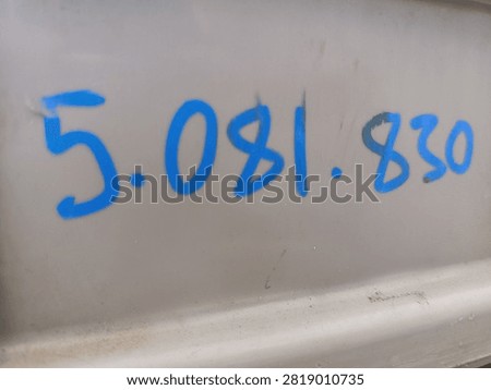 Close up of blue serial number code written on grey industrial surface