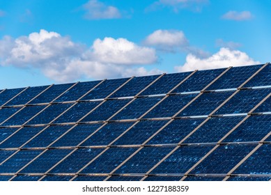 Close up of blue solar panel array, with blue sky and white clouds in background
 - Shutterstock ID 1227188359