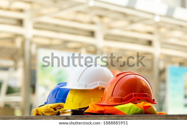 Close up Blue, yellow, white\
and red hard safety helmet hats for safety project of workman as\
engineering or project worker place on concrete floor city\
outdoor.