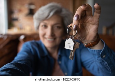 Close up blurred of happy elderly 60s grandmother show keys excited about house bank mortgage or lease, smiling mature woman tenant renter overjoyed to be home owner, relocation, rental concept