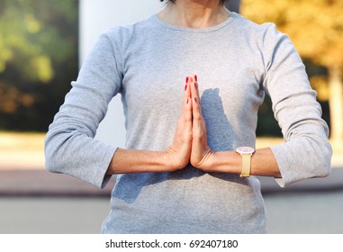 Close Up Of Body Woman Doing Yoga Gesture Outdoors. Relaxed Mature Woman Pressing Hands Together During Yoga