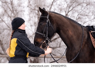 Close bond between person and horse in winter. Young woman and a horseback - Powered by Shutterstock