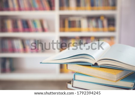 Close up book stack on the table in the library room and blurred space of bookshelf background