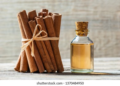 Close up bottle of cinnamon oil with cinnamon sticks and cinnamon powder on wooden background, healthy spice concept Cinnamomum verum
